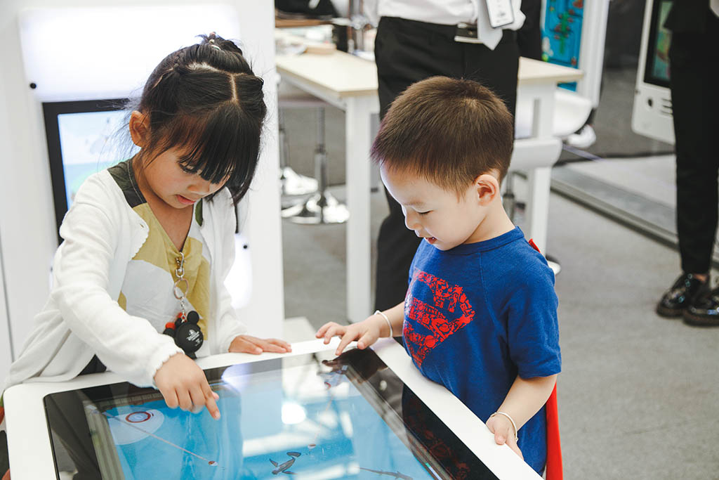 Deux enfants occupés à jouer avec les systèmes de jeux interactifs de l'IKC